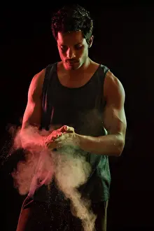 Balance Prints: Man standing in front of a dark background with white powder in his hand