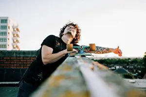 Boarding Prints: man stood on the top of a building with his skateboard looking up