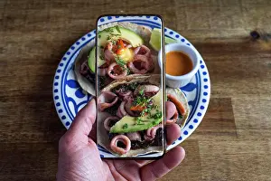 Produce Prints: Man taking photos of Mexican food on the table. Squid tacos