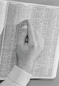 Pointing Prints: Man's hand on phone book's page open on Manhattan