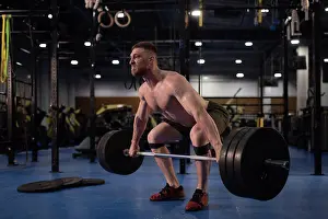 Heavy Prints: Masculine weightlifter squatting with barbell