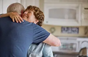 50 To 55 Years Prints: Mature couple embracing in their kitchen