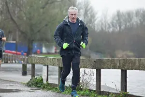 Jogging Prints: A mature man jogging along a waterside path on an overcast day