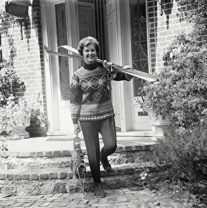Full Length Prints: Mature woman carrying skis and a pair of ski boots