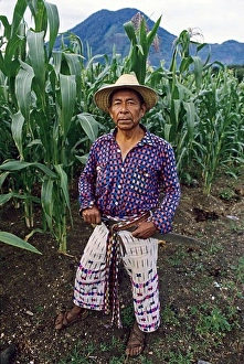 Indians Prints: Mayan corn farmer wearing traditional hand woven clothing pauses under the San Pedro volcano near Lake Atitlan