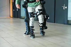 Disability Prints: Mechanical exoskeleton, physiotherapist walking with unrecognizable disabled person with robotic skeleton