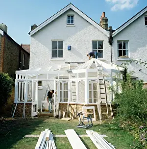 Exteriors Prints: Men building a conservatory on the back of a white Victorian terraced house