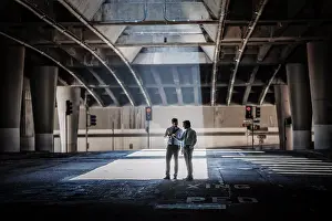 Walkway Prints: Two men in an urban underpass, with concrete and glass structures surrounding them