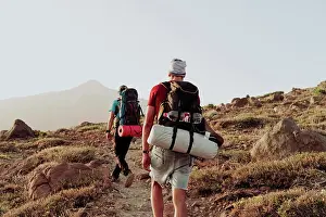 Canary Islands Prints: Two men walk on trail with camping gear and Mount Teide in background