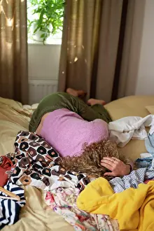 Komfort Prints: menopause Woman lying face down on a messy bed with clothes scattered around