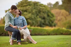 30 To 35 Years Prints: Mid adult couple sitting on a chair and kissing