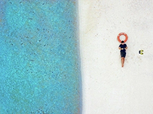 35 To 40 Years Prints: Mid adult male tourist lying with inflatable ring at tropical beach
