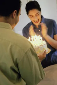 Life Events Prints: Mid adult man holding a birthday cake in front of a mid adult woman
