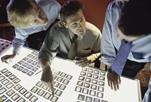 Meet Prints: Two mid adult men and a mid adult woman looking at slides