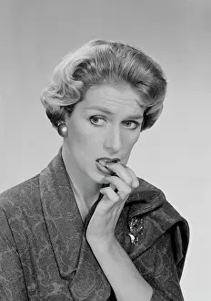 Worrying Prints: Mid adult woman biting her nails and looking away, studio shot
