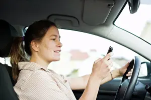 Join Prints: Mid adult woman dialing on mobile phone while driving