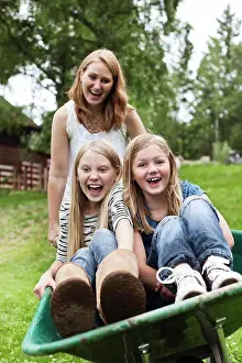 Out Door Prints: Mid adult woman pushing daughters in wheelbarrow