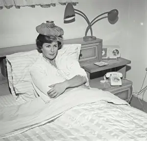 Fever Prints: Mid adult woman reclining on the bed with an ice pack on her head