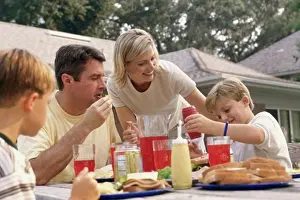 Sandwich Prints: Mid adult woman serving food to her husband and two sons