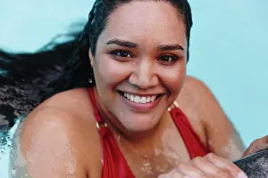 Voluptuous Prints: Mid adult woman with wet hair holding onto outdoor swimming poolside