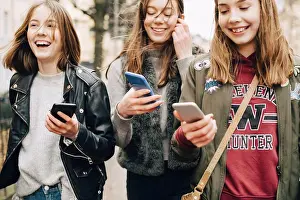 Using Phone Prints: Midsection of female friends using mobile phone while walking in city