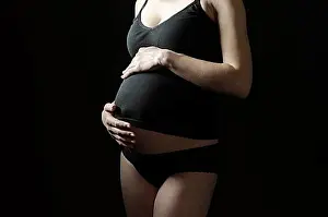 Parenting Prints: Midsection of pregnant woman in black clothes on a black background