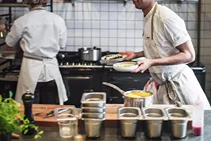 Chef Prints: Midsection of waiter carrying food plates in kitchen at restaurant