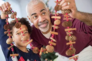 Mature Adult Prints: Mixed race grandfather and grandson holding Christmas decorations