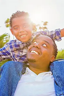 Assorted Prints: mixed-race son and african american father playing piggyback outdoors together