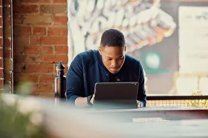 Cafe Prints: Mixed race young man working on a tablet at an outdoor cafe