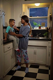 Fever Prints: Mom at home in kitchen with son sitting on counter checking his temperature while talking to doctors on the phone