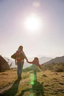 Back Ground Prints: Mom keeps daughter's hand and walks on the nature in sunset light