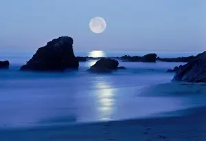 Pathway Prints: Moon setting over rocky shore along Pacific Coast in Laguna Beach, California