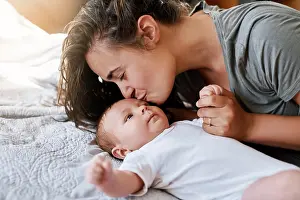 Maternity Prints: Mother, baby and forehead kiss on bed in home for support
