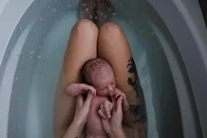 Beginnings Prints: Mother with baby son on her lap in bath, cropped overhead view