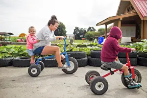 Small Group Prints: Mother biking on tricycles with her two kids outdoors