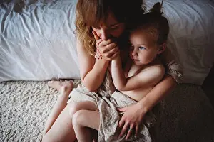 Gorgeous Prints: Mother with closed eyes while kissing daughter in bedroom showing skin