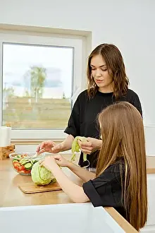 Concentrate Prints: Mother and daughter tearing iceberg lettuce leaves into pieces while making food at home