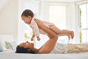 Lifting Prints: Mother, lifting baby and bedroom in family home for bonding