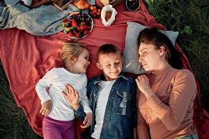 Small Group Prints: Mother looking at children lying on picnic blanket in field