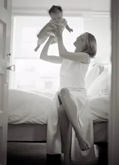 Verticals Prints: A mother is playing with her baby in the bedroom