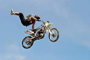 Exhilaration Prints: A motocross rider performing a stunt while flying through the air on his motorcycle in a blue sky background