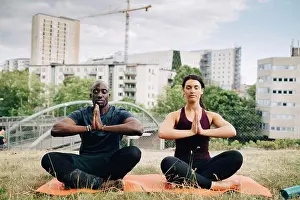 Midadult Men Prints: Multi-ethnic friends practicing yoga on field against buildings in city