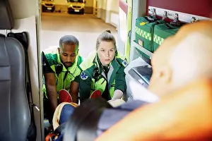 Frgbild Prints: Multi-ethnic paramedics pulling out patient together from ambulance
