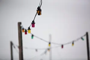 Weather Prints: A multicoloured string of electric lights against a grey sky