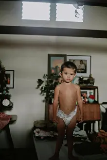 : Multiracial Asian toddler boy standing on a table in his diaper