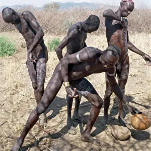 Brass Prints: Mursi men decorate their bodies with patterns using white clay in preparation for a dance