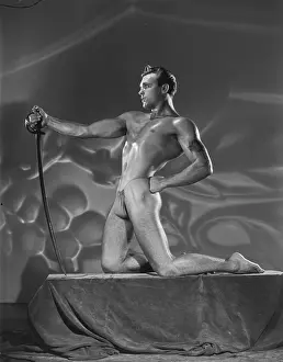 Bodybuilder Prints: Muscular Bodybuilder Kneels with Sword c.1951