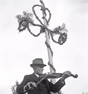 Black Andwhite Prints: Musician at midsummer. An elderly man is playing the violin at an open air midsummer fiest