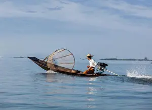 Paddle Prints: Myanmar travel attraction landmark - Traditional Burmese fisherman with fishing net at Inle lake in speeding motor boat